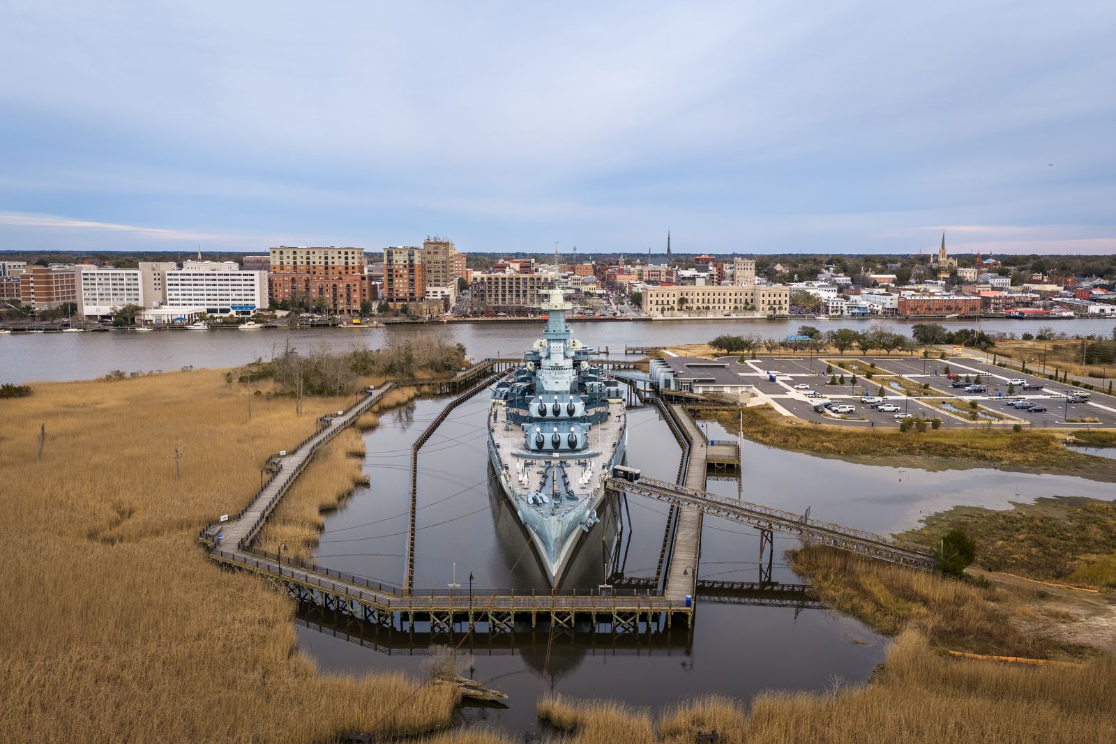 Aerial view of the Battleship North Carolina in Wilmington with the downtown skyline behind it