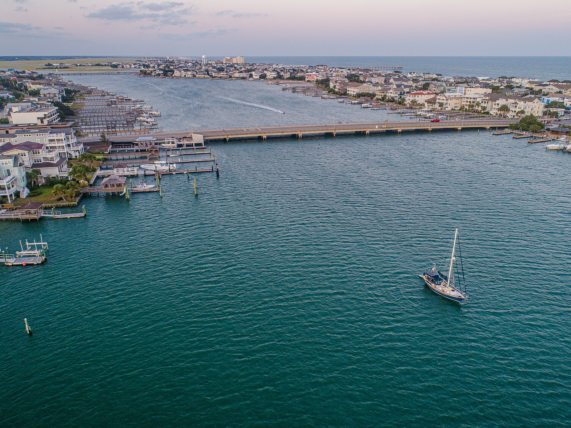 Aerial view of Wrightsville Beach with a sailboat anchored in the channel