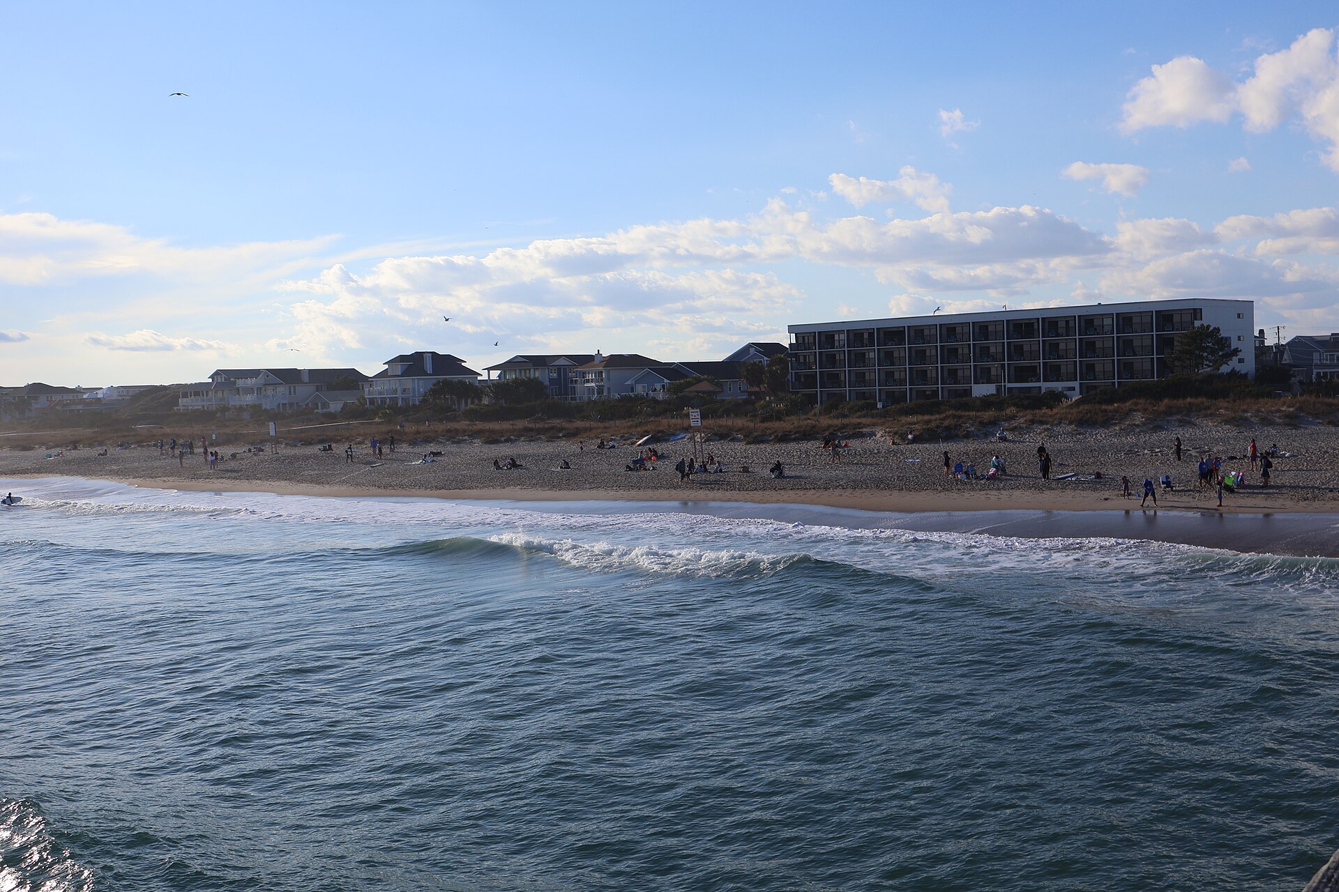 Waves rolling onto Wrightsville Beach with coastal homes along the shore