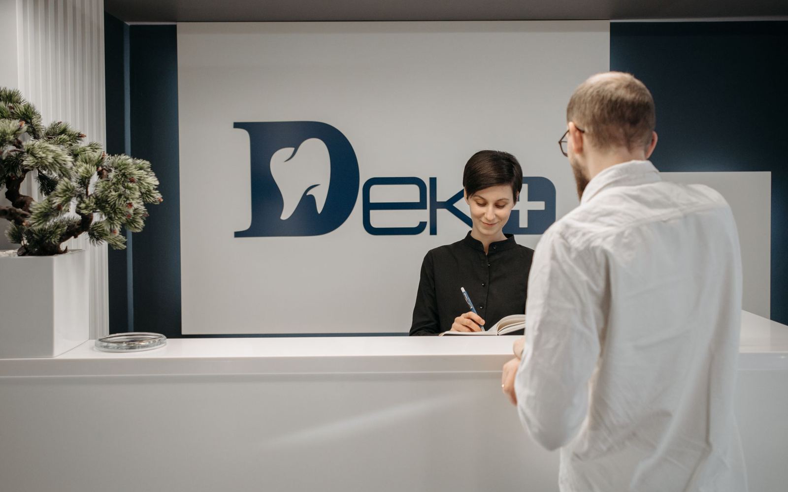 A receptionist helping a visitor at the front desk