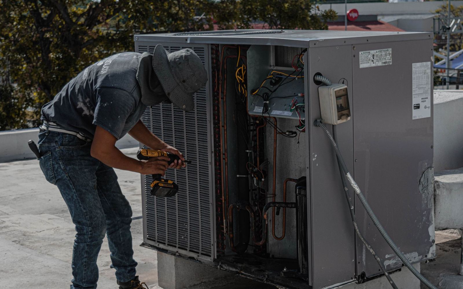 A technician repairing a rooftop air conditioning unit